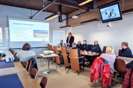 Kokoushuoneessa joukko ihmisiä seuraamassa esitystä hevosurheiluhankkeesta.